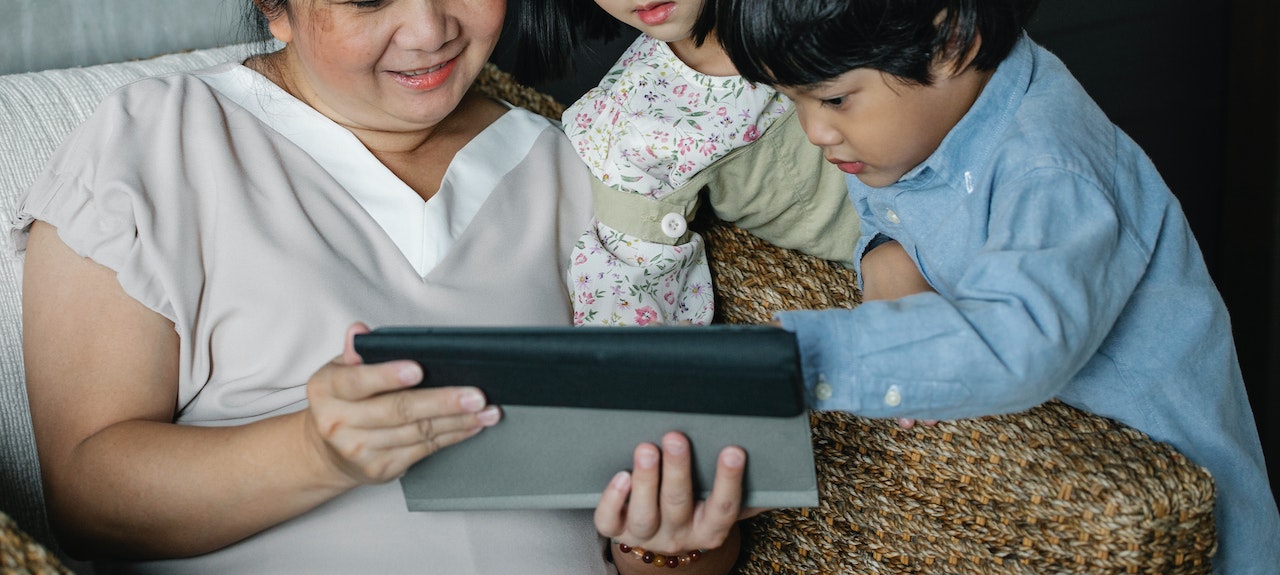 woman with grandchildren watching video on tablet