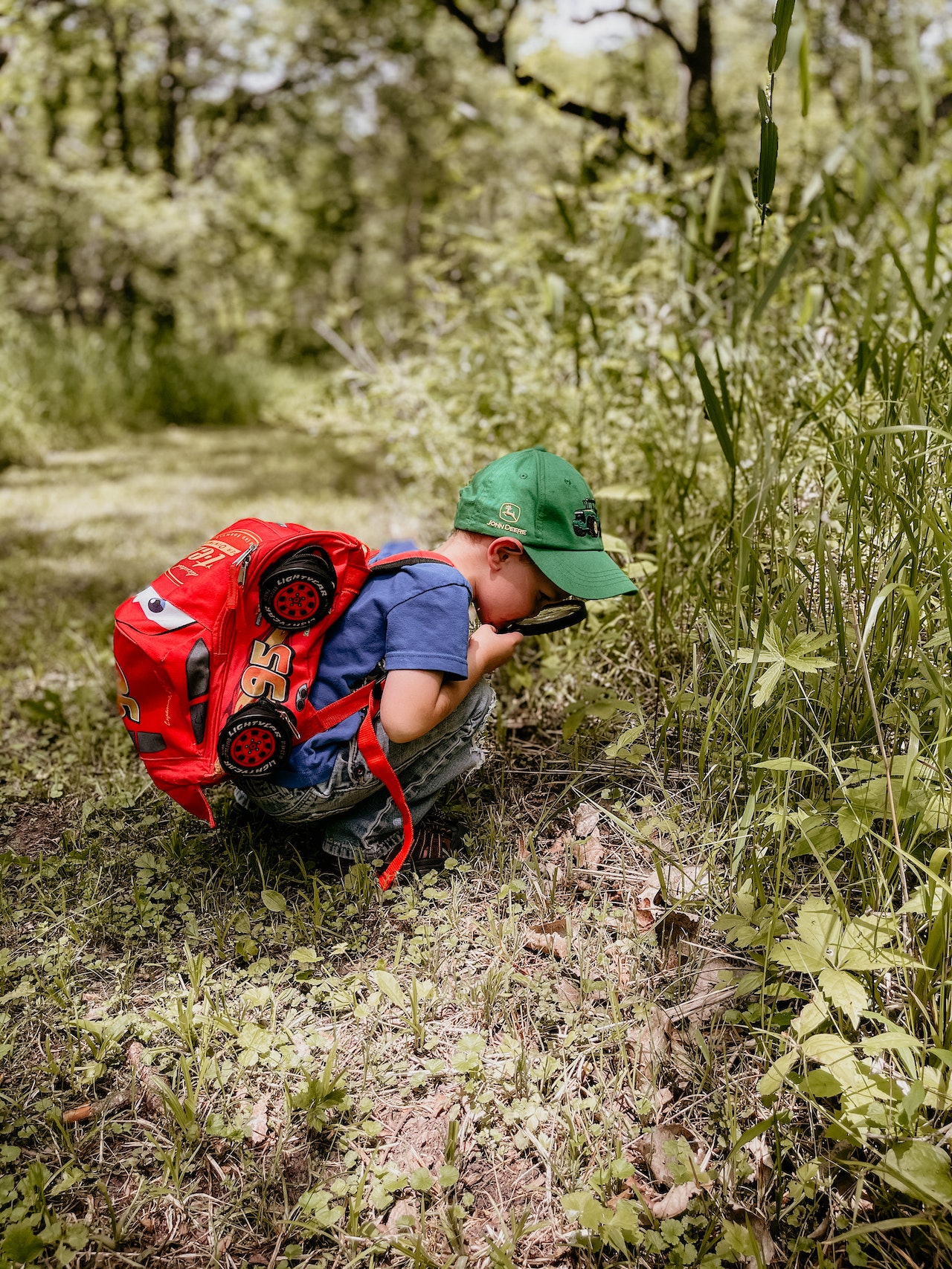 Child examining a plant with a magnifying glass