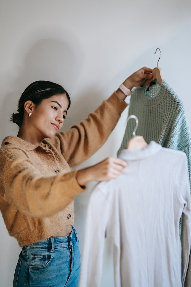Woman looking at two pieces of clothing